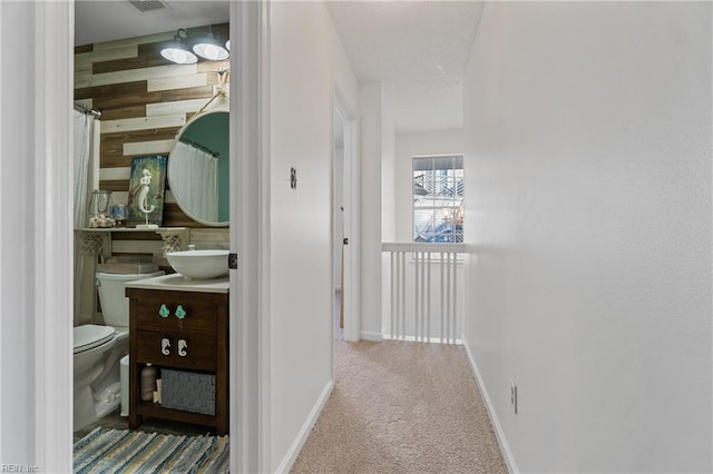 hall with carpet, sink, and wood walls