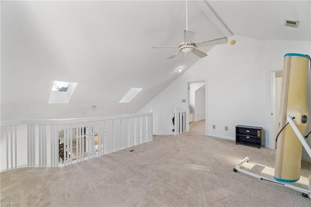 additional living space featuring ceiling fan, light colored carpet, and lofted ceiling with skylight