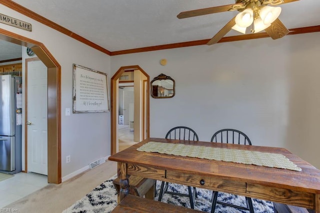 carpeted dining area with ornamental molding and ceiling fan