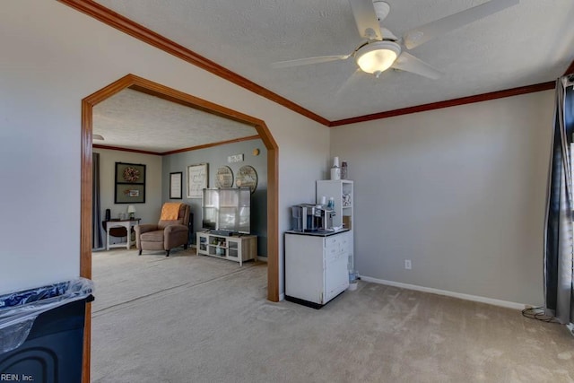 interior space featuring a textured ceiling, ceiling fan, crown molding, and light colored carpet