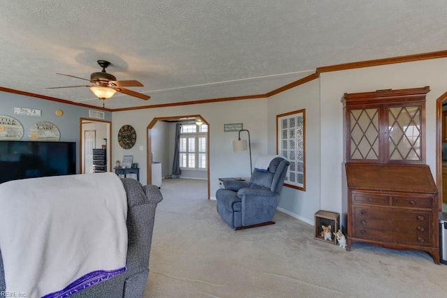 carpeted living room featuring a textured ceiling, ceiling fan, and ornamental molding