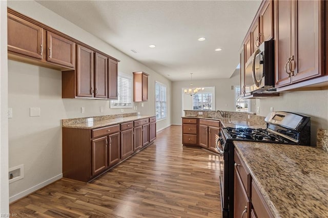 kitchen with light stone counters, hanging light fixtures, dark hardwood / wood-style floors, a chandelier, and appliances with stainless steel finishes