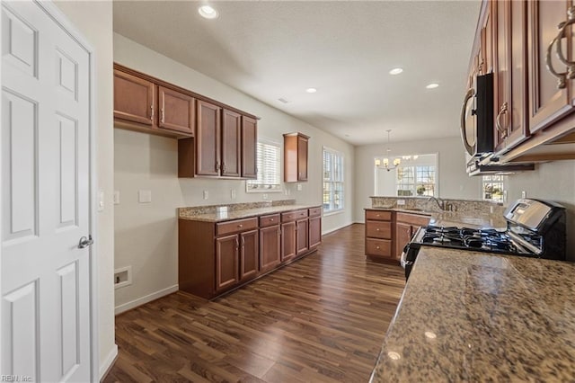 kitchen with decorative light fixtures, an inviting chandelier, stove, and light stone countertops