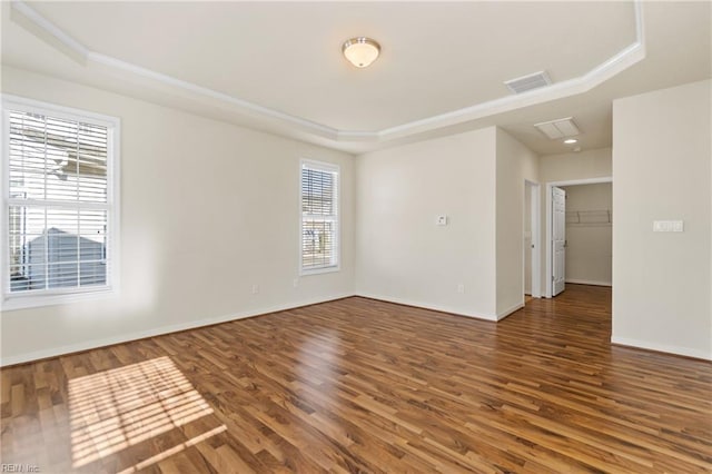 unfurnished room featuring dark wood-type flooring and a tray ceiling