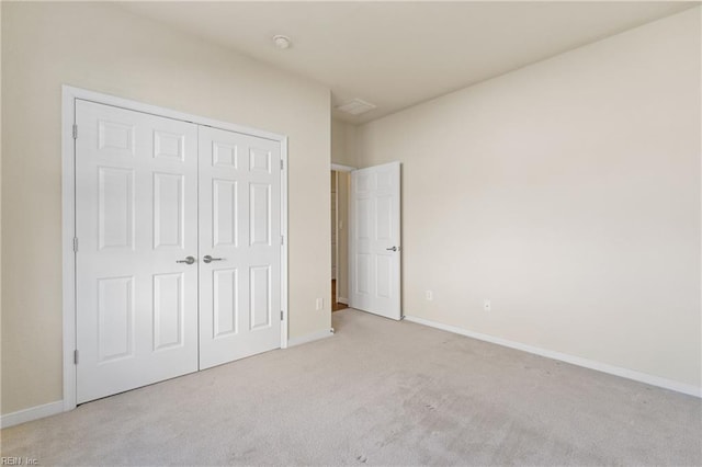 unfurnished bedroom featuring light colored carpet and a closet