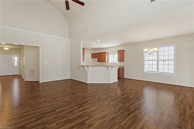 unfurnished living room with ceiling fan with notable chandelier, lofted ceiling, and dark hardwood / wood-style floors