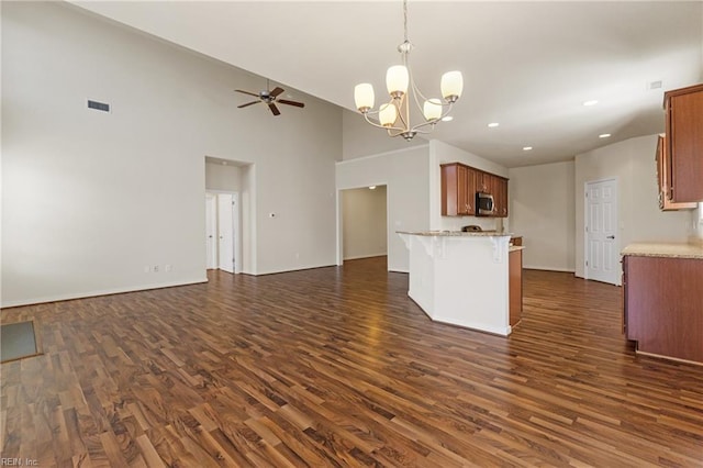 kitchen with hanging light fixtures, kitchen peninsula, dark hardwood / wood-style floors, a high ceiling, and ceiling fan with notable chandelier