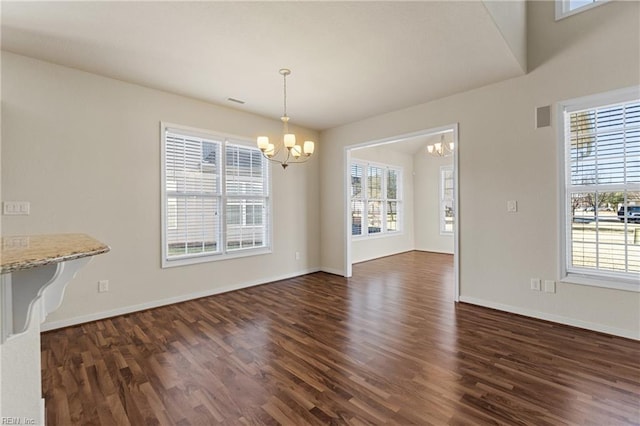 unfurnished dining area with a notable chandelier and dark hardwood / wood-style floors