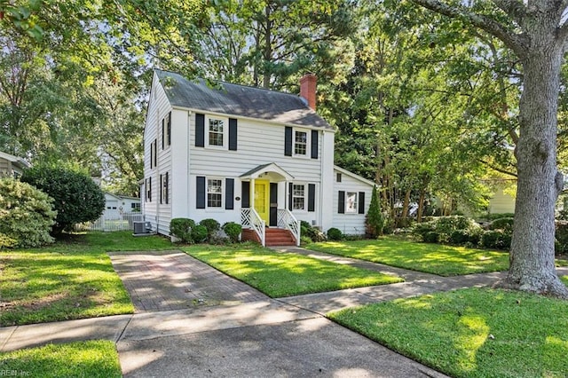 colonial home featuring cooling unit and a front lawn