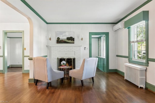 living area featuring ornamental molding, radiator, a brick fireplace, dark hardwood / wood-style floors, and a baseboard radiator