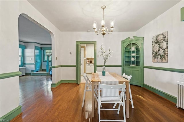 dining room with a notable chandelier, radiator heating unit, and dark hardwood / wood-style floors