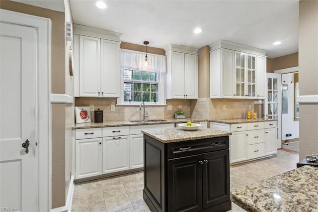 kitchen with sink, white cabinetry, pendant lighting, and light stone countertops