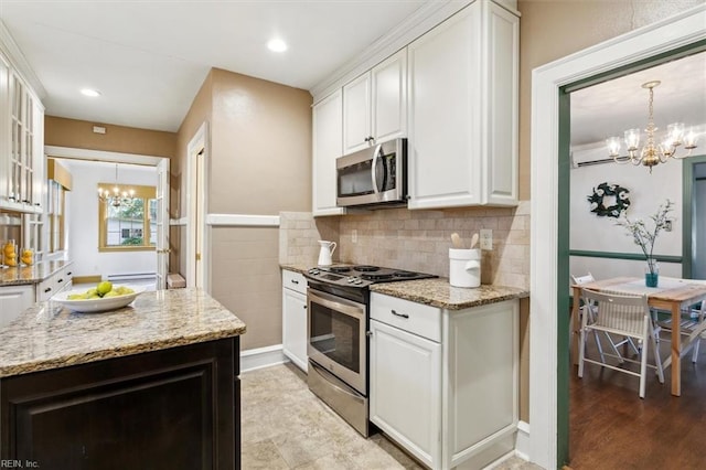 kitchen with light stone counters, white cabinets, appliances with stainless steel finishes, and a notable chandelier