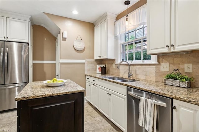 kitchen featuring appliances with stainless steel finishes, hanging light fixtures, light stone counters, sink, and white cabinetry