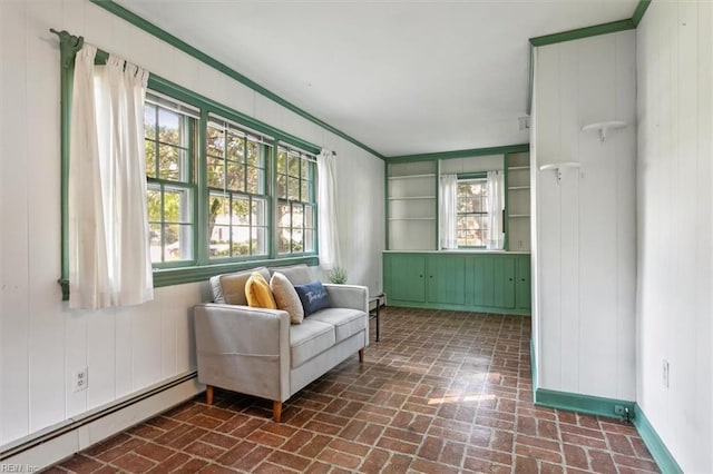 sitting room featuring baseboard heating, ornamental molding, and wooden walls