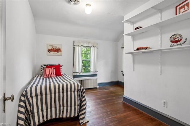 unfurnished bedroom featuring lofted ceiling, dark wood-type flooring, and radiator heating unit