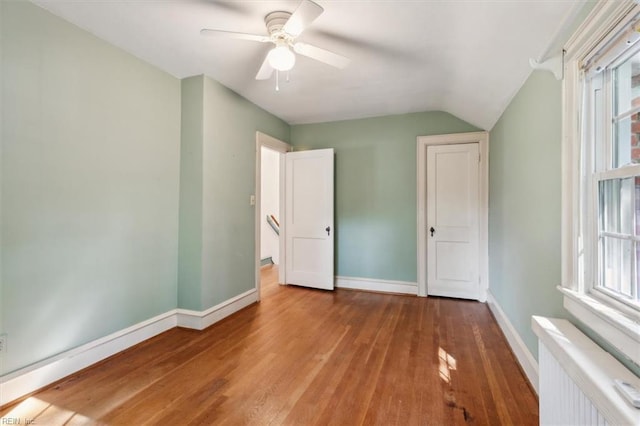 unfurnished bedroom featuring ceiling fan, light wood-type flooring, vaulted ceiling, and radiator