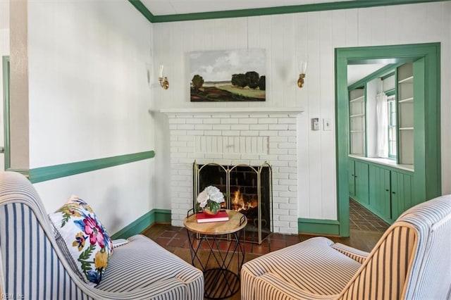 sitting room with a brick fireplace, wooden walls, crown molding, and dark hardwood / wood-style floors