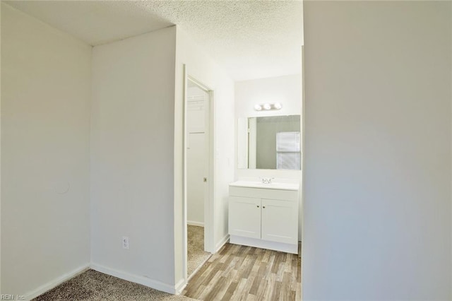 hallway with sink, a textured ceiling, and light hardwood / wood-style floors