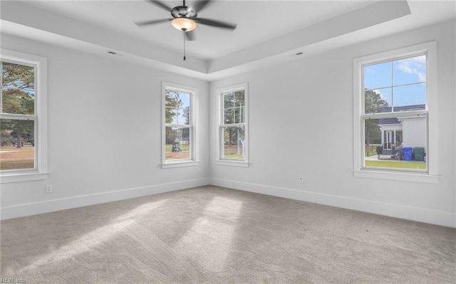 unfurnished room with a raised ceiling, ceiling fan, and carpet flooring