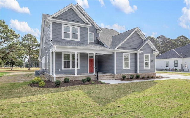 craftsman-style home with a front yard, covered porch, and central air condition unit