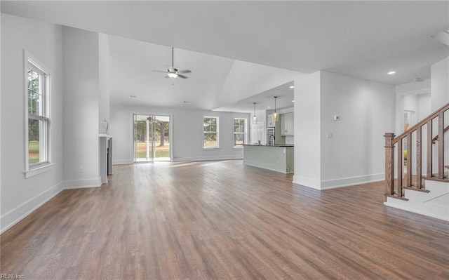 unfurnished living room featuring lofted ceiling, hardwood / wood-style floors, and ceiling fan