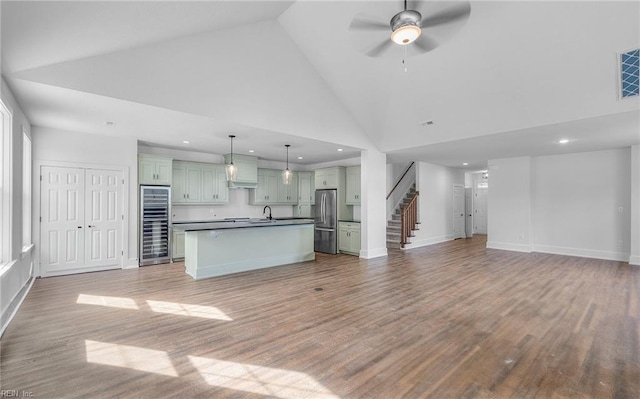 unfurnished living room with sink, high vaulted ceiling, ceiling fan, and hardwood / wood-style floors