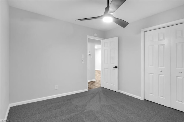 unfurnished bedroom with dark colored carpet, ceiling fan, and a closet