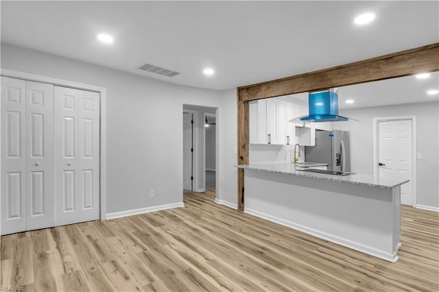 kitchen with white cabinets, light stone counters, light hardwood / wood-style flooring, kitchen peninsula, and stainless steel fridge with ice dispenser