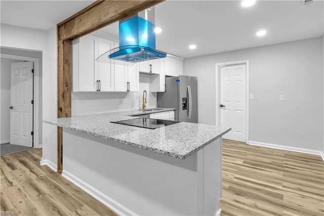 kitchen featuring white cabinets, island exhaust hood, kitchen peninsula, black electric cooktop, and stainless steel refrigerator with ice dispenser