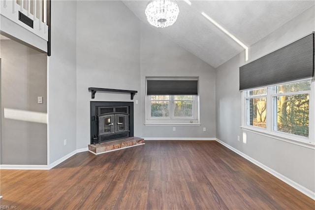 unfurnished living room featuring vaulted ceiling, dark wood-type flooring, a wealth of natural light, and an inviting chandelier