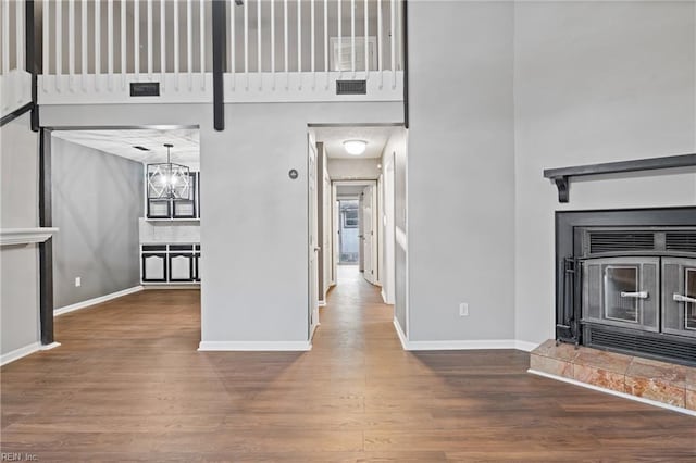 unfurnished living room featuring a towering ceiling, wood-type flooring, and a notable chandelier