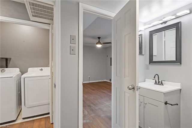 clothes washing area with ceiling fan, sink, independent washer and dryer, and light hardwood / wood-style flooring