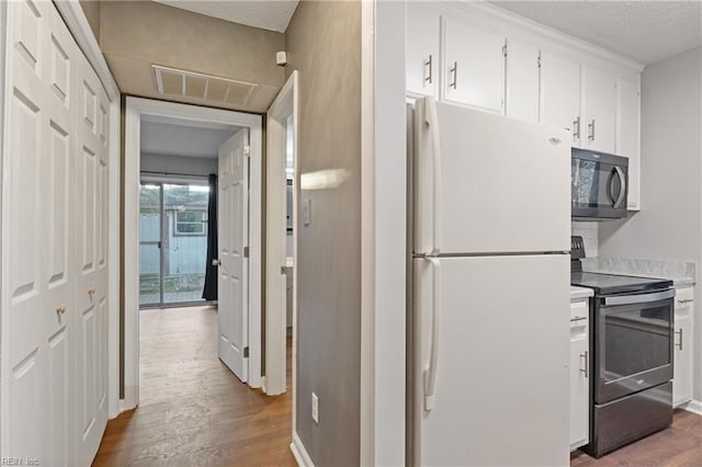 kitchen featuring white cabinetry, electric range, wood-type flooring, and white refrigerator