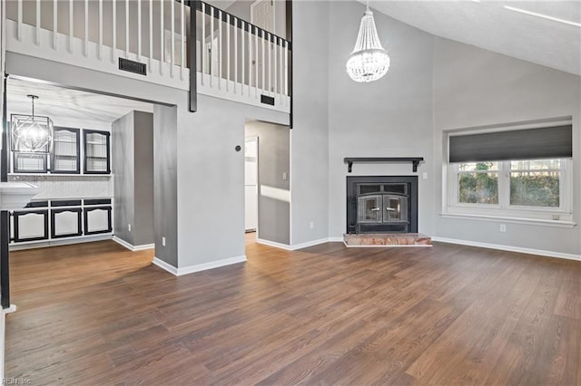 unfurnished living room with a notable chandelier, hardwood / wood-style flooring, and high vaulted ceiling