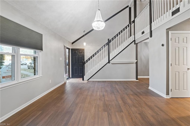 entrance foyer featuring high vaulted ceiling, dark wood-type flooring, and an inviting chandelier