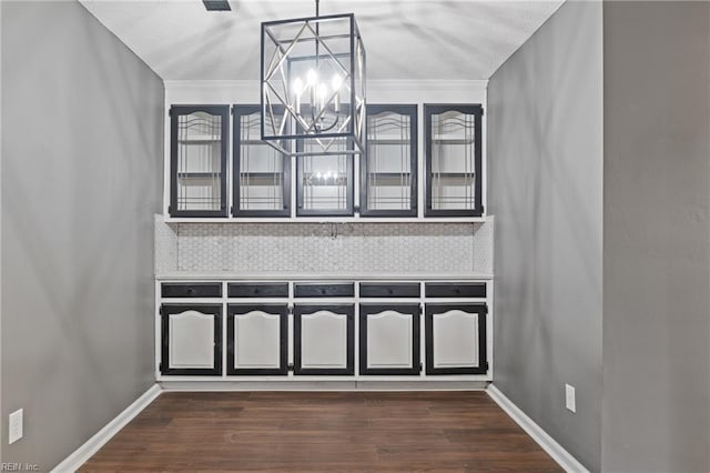 interior details with backsplash, hardwood / wood-style floors, and a chandelier