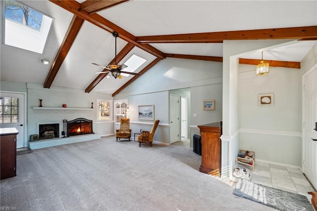 living area featuring ceiling fan, a skylight, light carpet, and a fireplace