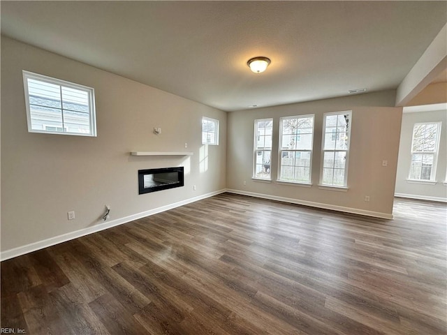 unfurnished living room featuring a healthy amount of sunlight and dark hardwood / wood-style flooring