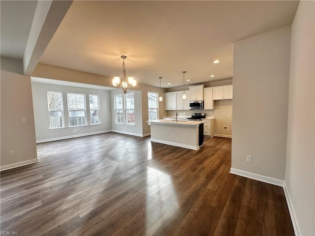 unfurnished living room featuring sink, dark hardwood / wood-style flooring, and an inviting chandelier