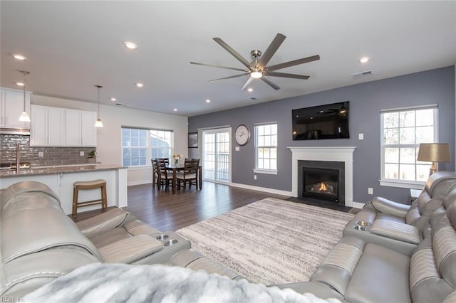 living room with dark wood-type flooring, ceiling fan, and sink