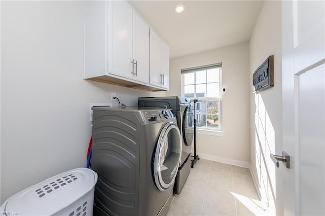 washroom with washing machine and dryer, cabinets, and light tile patterned floors