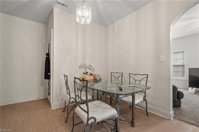 dining room with wood-type flooring and an inviting chandelier