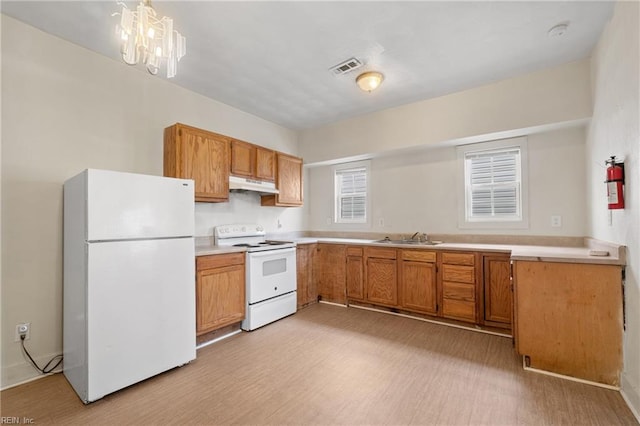 kitchen featuring sink, white appliances, light hardwood / wood-style flooring, and an inviting chandelier