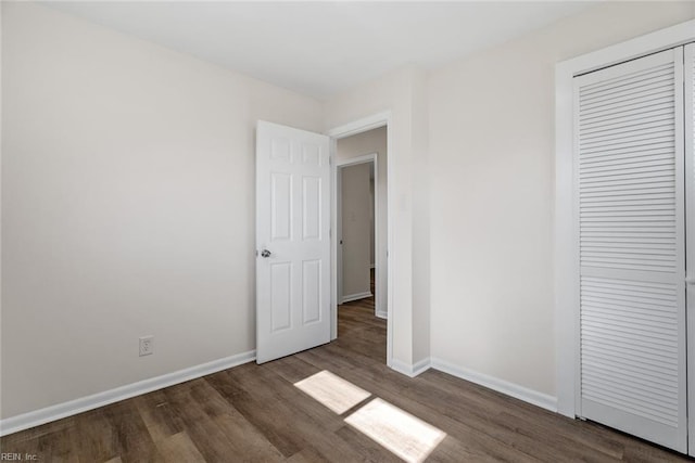 unfurnished bedroom with a closet and dark hardwood / wood-style floors