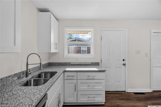 kitchen with sink, white cabinetry, stainless steel dishwasher, light stone countertops, and dark wood-type flooring