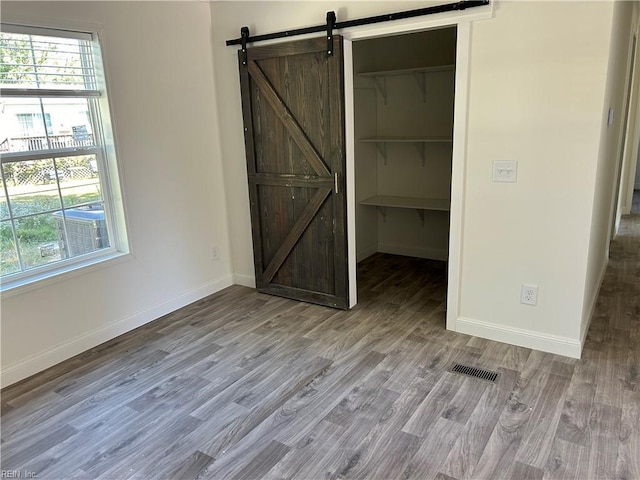 unfurnished bedroom with a barn door, a closet, a walk in closet, and multiple windows