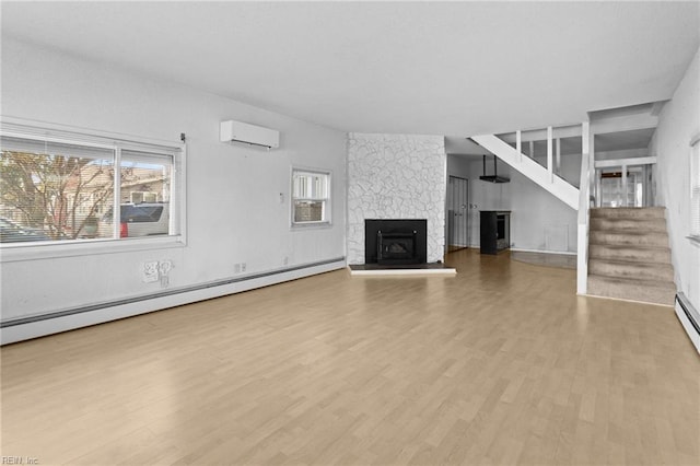 unfurnished living room with hardwood / wood-style flooring, a wall unit AC, a baseboard radiator, and a stone fireplace