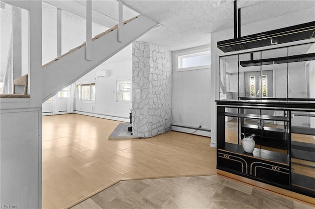 living room with a textured ceiling, baseboard heating, a wall mounted AC, and hardwood / wood-style flooring