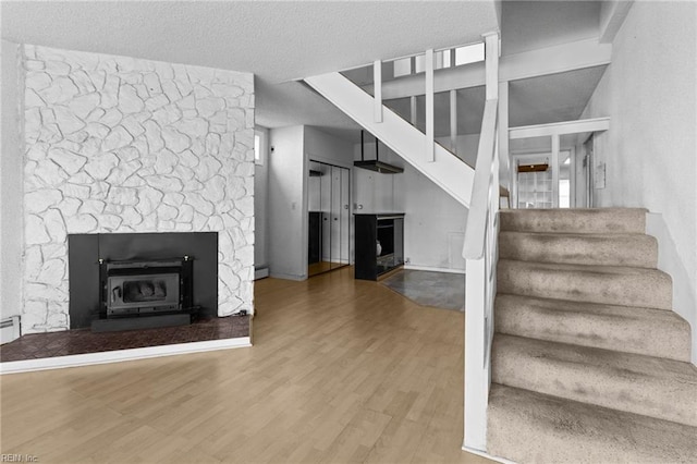 unfurnished living room with a baseboard heating unit, a fireplace, and hardwood / wood-style floors